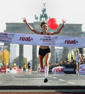 Eine Frau läuft gerade als Erste über die Ziellinie des Berliner Marathons